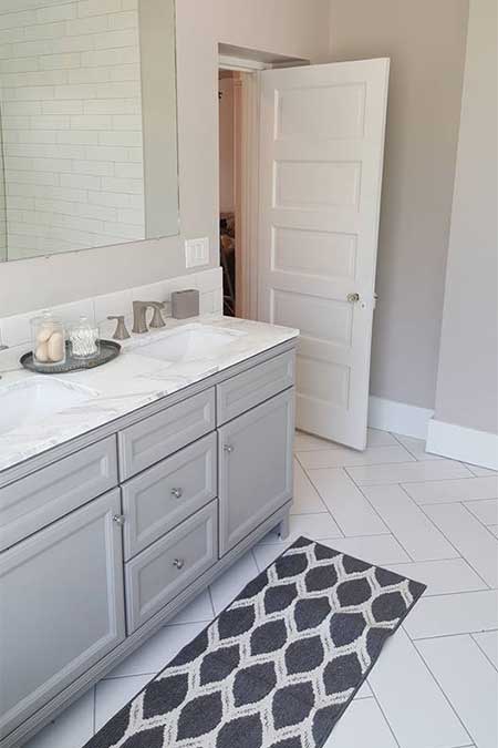 A bathroom with white tiles and a long carpet