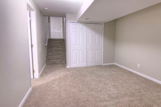 An empty room with stairs going up and double doors